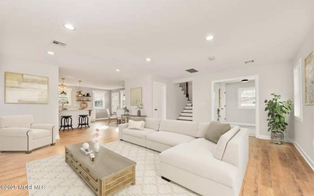 living area featuring recessed lighting, light wood-style flooring, visible vents, and stairway