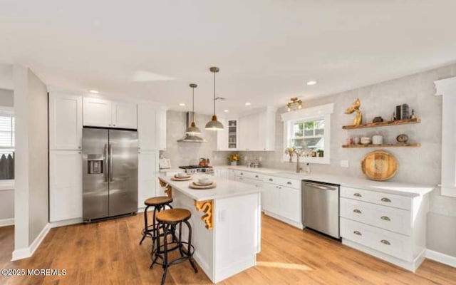kitchen featuring white cabinetry, light countertops, a breakfast bar area, light wood-type flooring, and stainless steel appliances