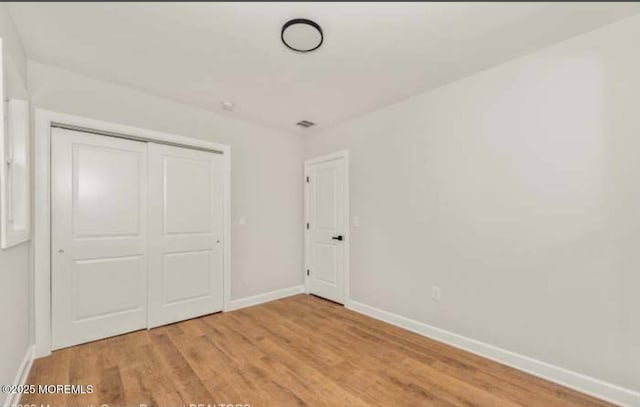 unfurnished bedroom with baseboards, a closet, and light wood-style floors