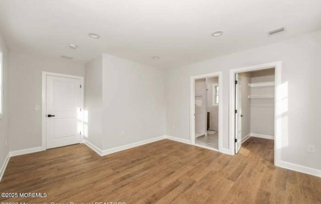 unfurnished bedroom featuring baseboards, visible vents, and wood finished floors