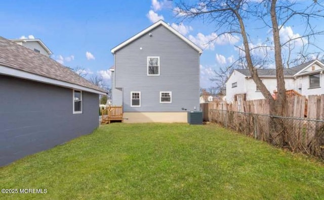 rear view of property with cooling unit, fence, and a yard