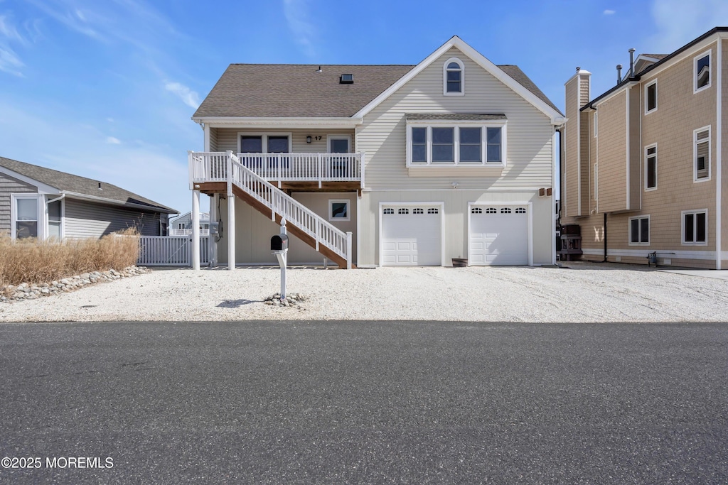 view of front of house featuring stairs, a garage, and gravel driveway
