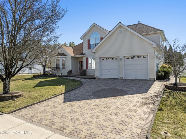 traditional-style house featuring a front yard, decorative driveway, and an attached garage