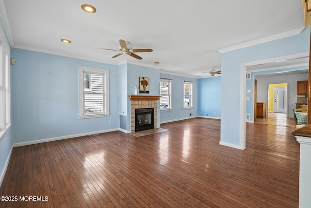 unfurnished living room featuring ceiling fan, a tiled fireplace, dark wood finished floors, crown molding, and baseboards