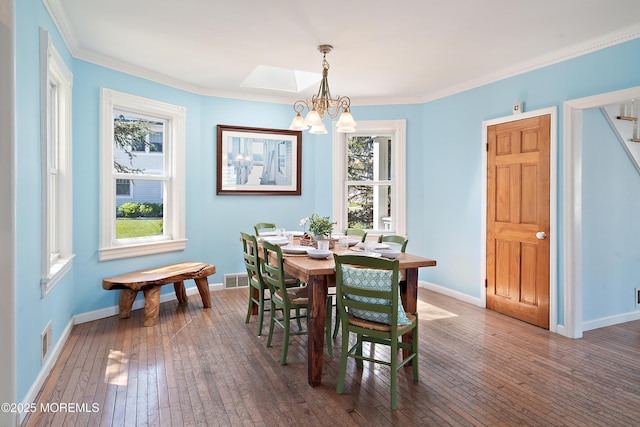 dining space with a chandelier, hardwood / wood-style floors, plenty of natural light, baseboards, and crown molding
