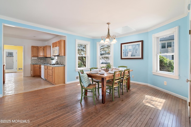 dining space with a chandelier, light wood-type flooring, baseboards, and ornamental molding