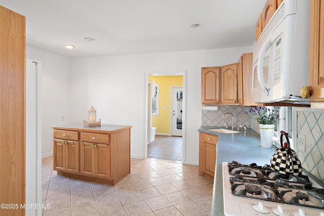 kitchen featuring white appliances, a sink, light tile patterned floors, backsplash, and baseboards