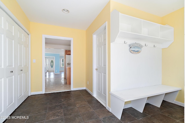 mudroom featuring baseboards and dark stone finish floors