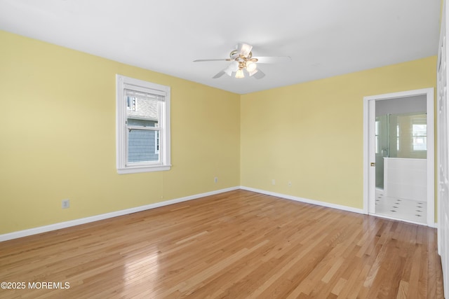 spare room featuring ceiling fan, plenty of natural light, light wood-style floors, and baseboards