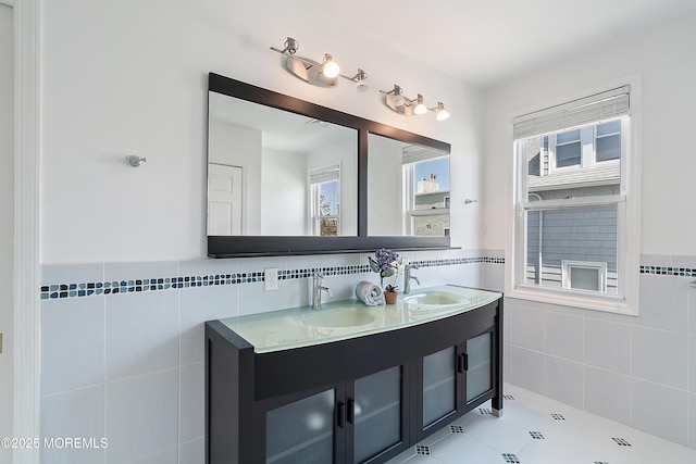 full bath with tile walls, healthy amount of natural light, a wainscoted wall, tile patterned flooring, and double vanity