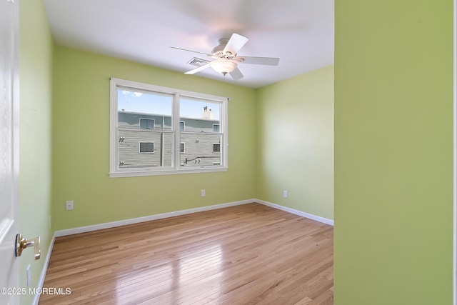 spare room featuring light wood finished floors, ceiling fan, and baseboards