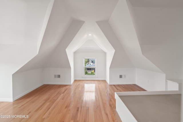 bonus room featuring light wood finished floors, baseboards, and lofted ceiling