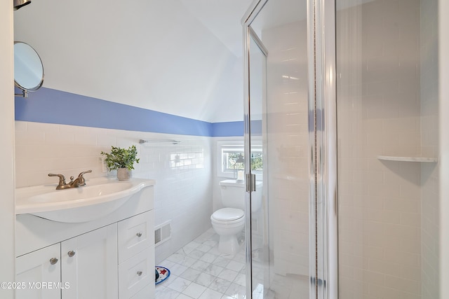 full bathroom featuring tile walls, a stall shower, toilet, vanity, and lofted ceiling