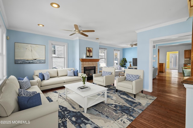living area featuring ceiling fan, a tiled fireplace, ornamental molding, healthy amount of natural light, and recessed lighting