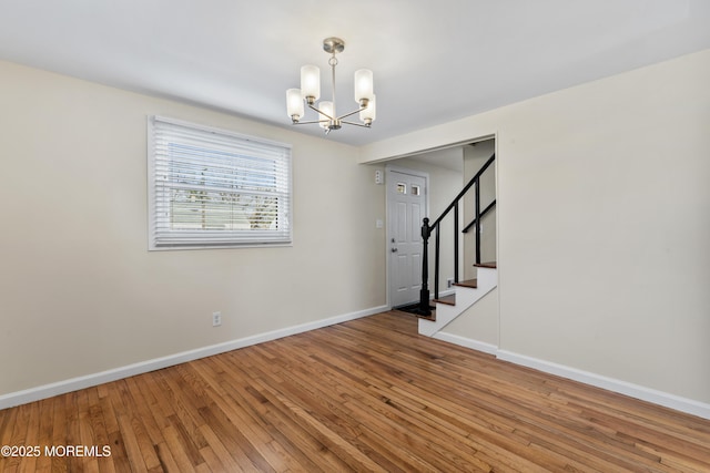 89 Barkalow Ave, Freehold, NJ 07728 - spare room featuring baseboards, stairway, hardwood / wood-style floors, and a chandelier