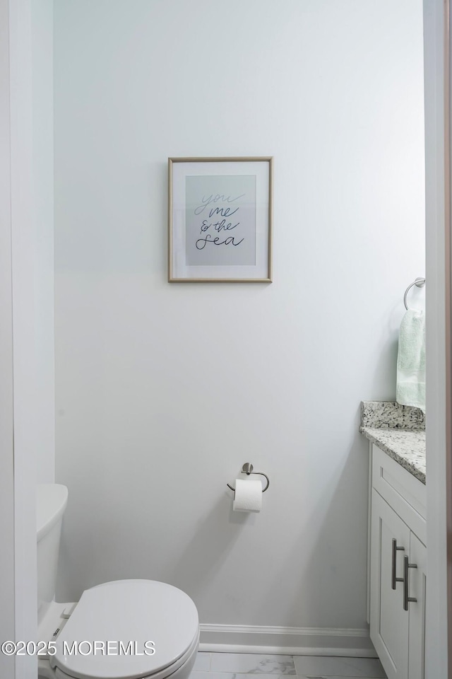 bathroom with marble finish floor, baseboards, toilet, and vanity