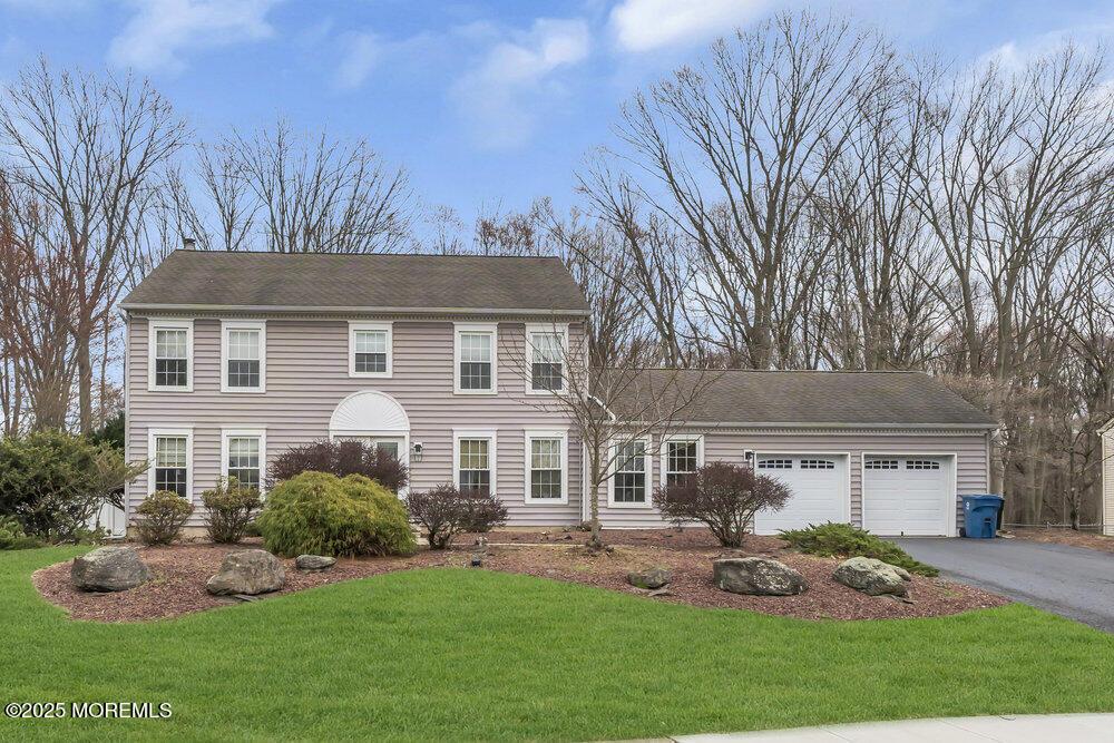 colonial house featuring driveway, a garage, and a front yard