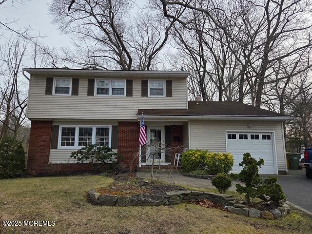 view of front of house featuring a front yard, a chimney, brick siding, aphalt driveway, and a garage