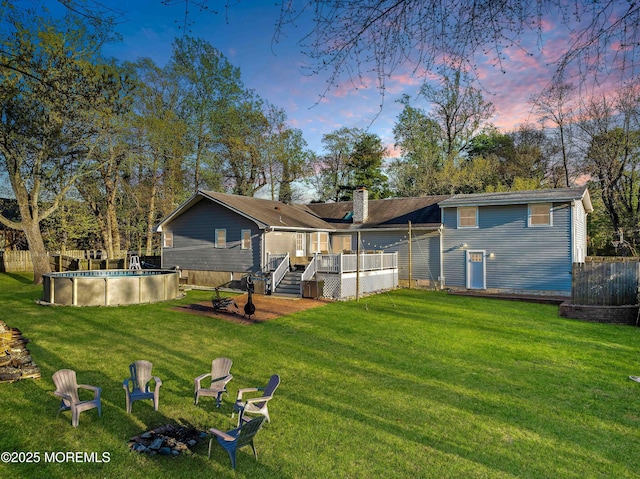113 Parker Rd, West Long Branch, NJ 07764 - back of property at dusk with a deck, fence, an outdoor pool, a chimney, and a lawn