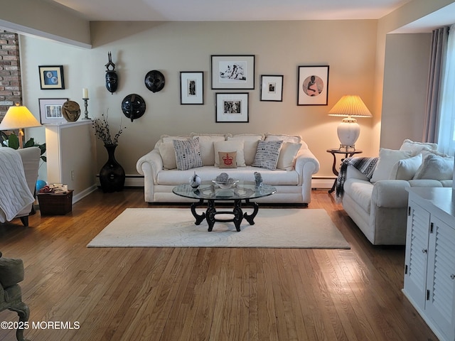 living area with baseboards, a baseboard heating unit, wood finished floors, and baseboard heating