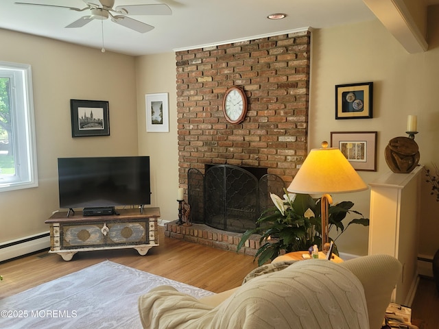 living room with ceiling fan, a baseboard radiator, wood finished floors, and a fireplace