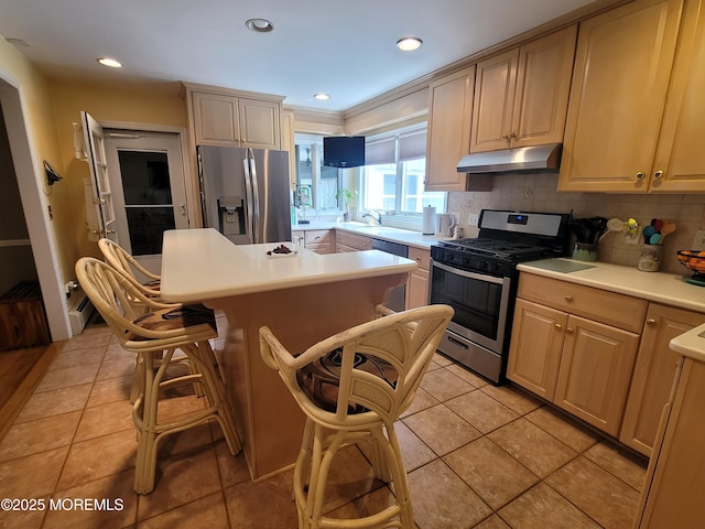 kitchen with a breakfast bar area, appliances with stainless steel finishes, tasteful backsplash, a center island, and under cabinet range hood