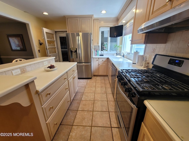 kitchen with decorative backsplash, light countertops, under cabinet range hood, a sink, and appliances with stainless steel finishes