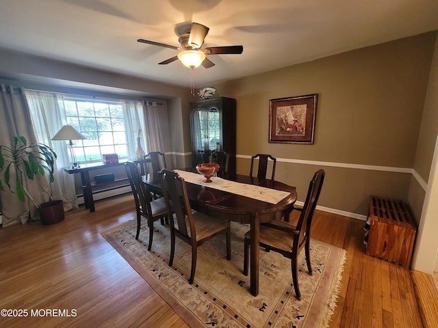 dining area featuring baseboards, ceiling fan, wood finished floors, and baseboard heating