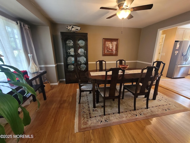dining room featuring ceiling fan, baseboards, and light wood-type flooring