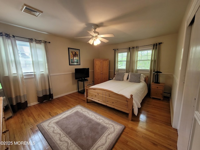 bedroom with ceiling fan, visible vents, baseboards, a baseboard radiator, and light wood-style flooring