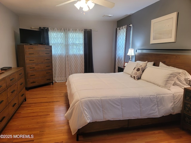 bedroom featuring a ceiling fan, visible vents, and light wood-style flooring