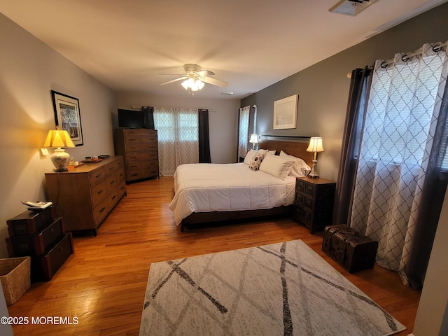 bedroom featuring light wood-type flooring, ceiling fan, and visible vents