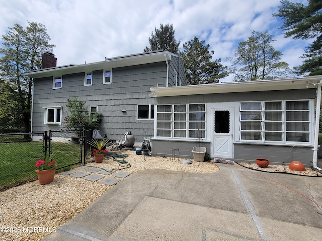 back of property featuring fence, a chimney, a gate, and a patio area