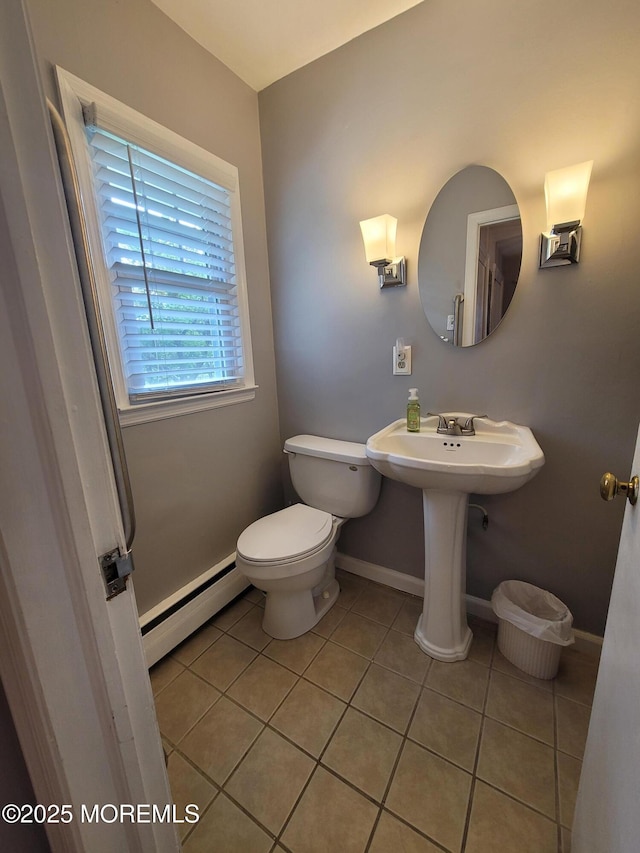 half bathroom featuring baseboards, a baseboard heating unit, tile patterned floors, and toilet