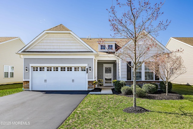 view of front facade with stone siding, aphalt driveway, a garage, a front yard, and roof with shingles