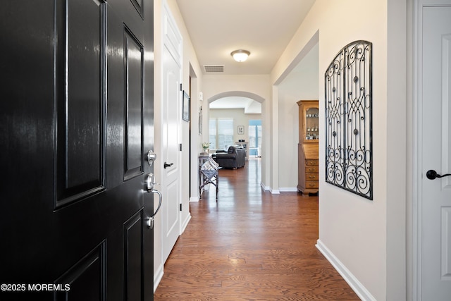 entryway with visible vents, arched walkways, baseboards, and wood finished floors