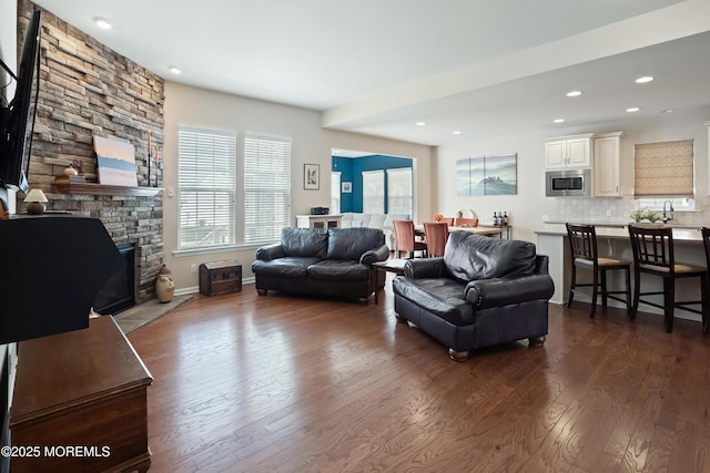 living room with dark wood finished floors, baseboards, a fireplace, and recessed lighting