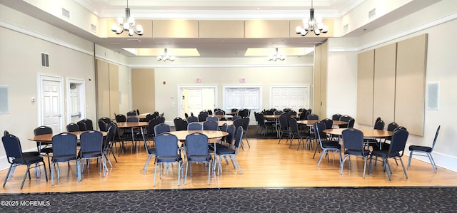 dining area featuring a towering ceiling, visible vents, and a chandelier