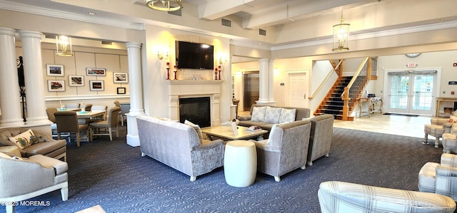 living room with stairs, crown molding, a glass covered fireplace, beamed ceiling, and ornate columns