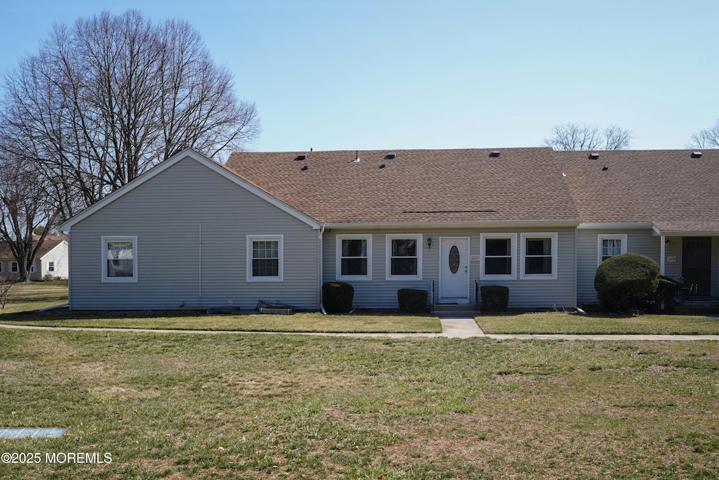view of front facade featuring a shingled roof and a front yard