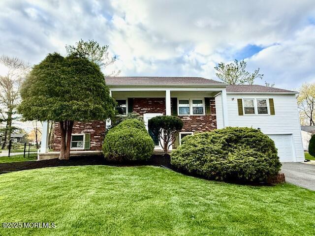 65 River Dr, Marlboro, NJ 07746 - bi-level home featuring a front lawn, brick siding, and a garage