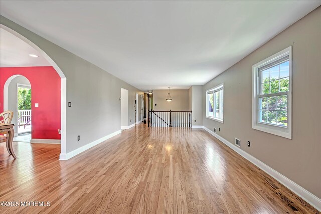 7 Mill Rd, Jamesburg, NJ 08831 - unfurnished living room with visible vents, light wood-style flooring, arched walkways, and baseboards