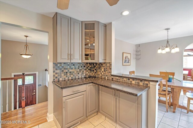 7 Mill Rd, Jamesburg, NJ 08831 - kitchen featuring light tile patterned floors, pendant lighting, glass insert cabinets, a peninsula, and backsplash