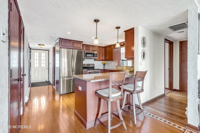 148 Royal Dr, Brick, NJ 08723 - kitchen with a textured ceiling, a peninsula, stainless steel appliances, visible vents, and light wood-style floors
