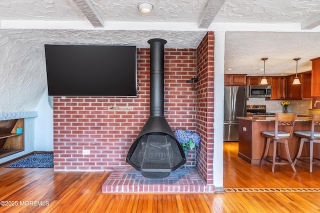 148 Royal Dr, Brick, NJ 08723 - details featuring a wood stove, a textured ceiling, backsplash, appliances with stainless steel finishes, and wood finished floors