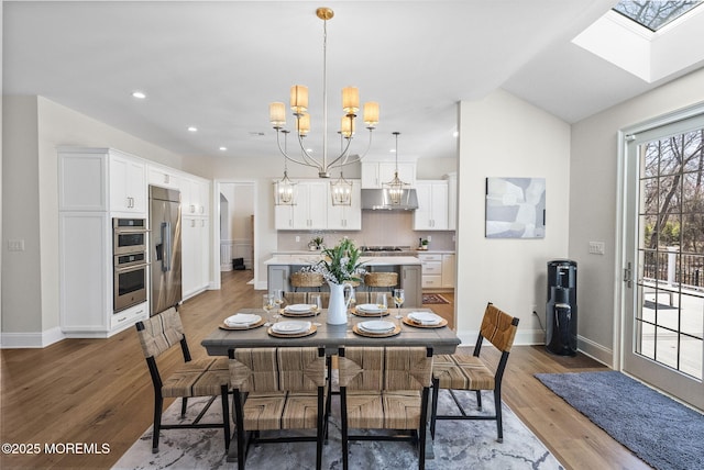 61 Windermere Rd, Lincroft, NJ 07738 - dining space with light wood-style flooring, a notable chandelier, a skylight, and baseboards