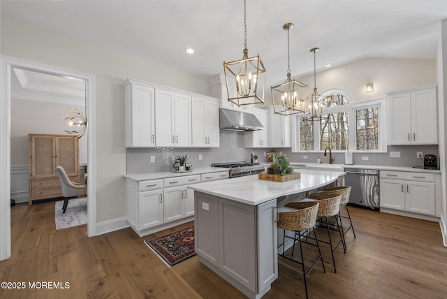 61 Windermere Rd, Lincroft, NJ 07738 - kitchen featuring hardwood / wood-style flooring, stainless steel appliances, under cabinet range hood, a breakfast bar area, and an inviting chandelier