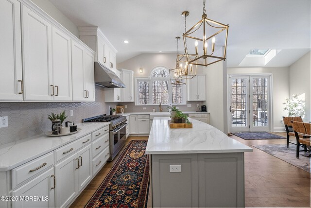 61 Windermere Rd, Lincroft, NJ 07738 - kitchen featuring lofted ceiling with skylight, under cabinet range hood, high end stove, a kitchen island, and white cabinets