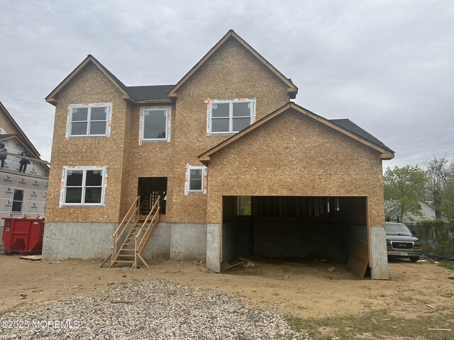 rear view of house with a garage, dirt driveway, and stucco siding