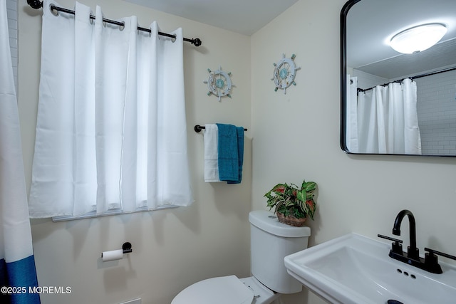 bathroom with a shower with curtain, toilet, and a sink